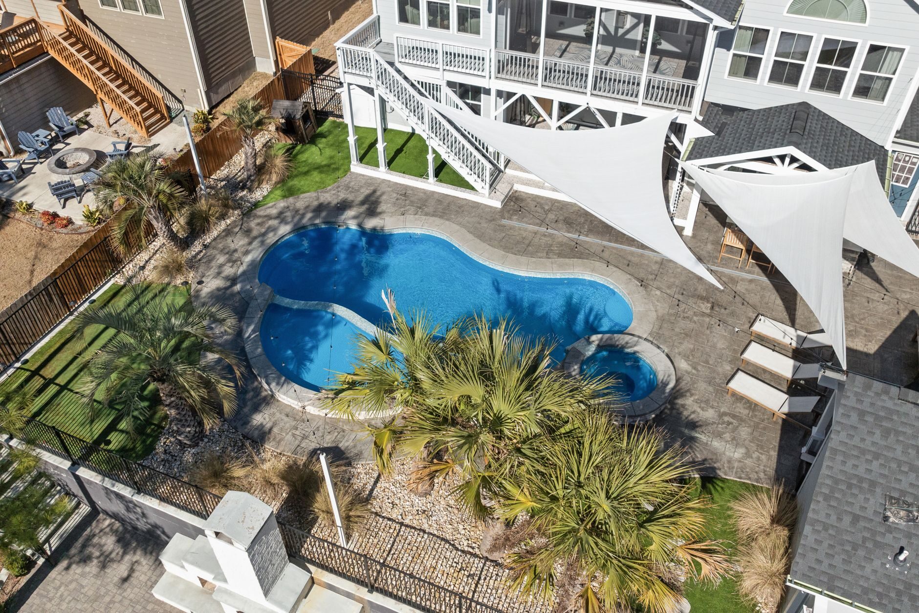 Concrete pool deck surrounding a backyard pool